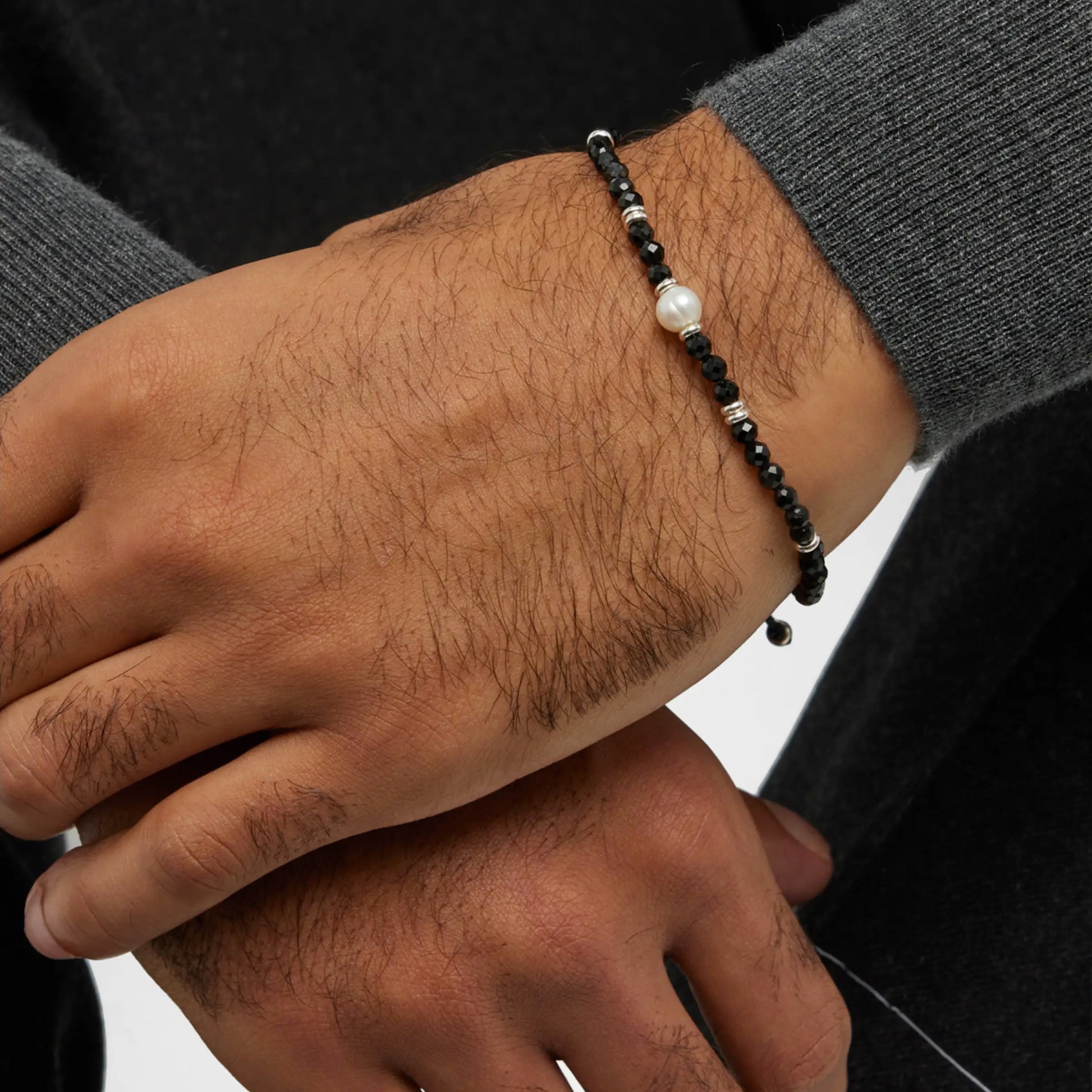 Close up of male models wrist wearing the Men's Black Onyx Beaded Bracelet with Freshwater Pearl Center by Jan Leslie of NYC. 