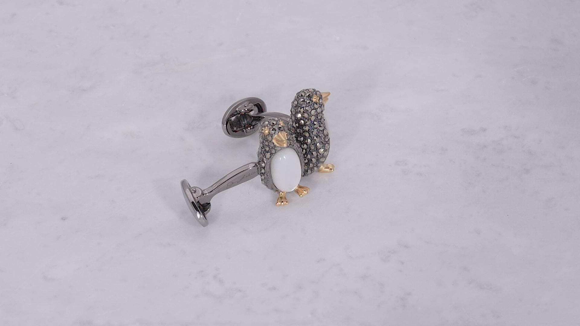 Video of 180 degree view of Jan Leslie's Gemstone Penguin with Marcasite, Mother of Pearl & Sterling Silver Cufflinks on marble background. 