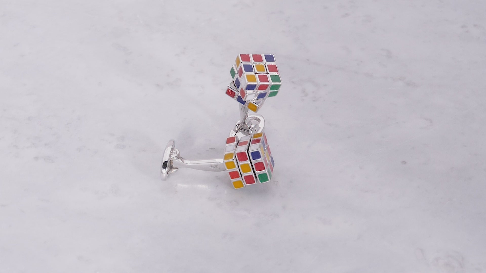 180 video of the Moving Puzzle Cube Multi Color Enamel & Sterling Silver Cufflinks on a marble background. 