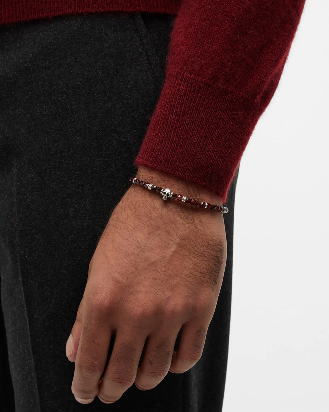 Close up of male models wrist donning the Faceted Garnet Gemstone Beaded Bracelet with Sterling Silver Skull. 