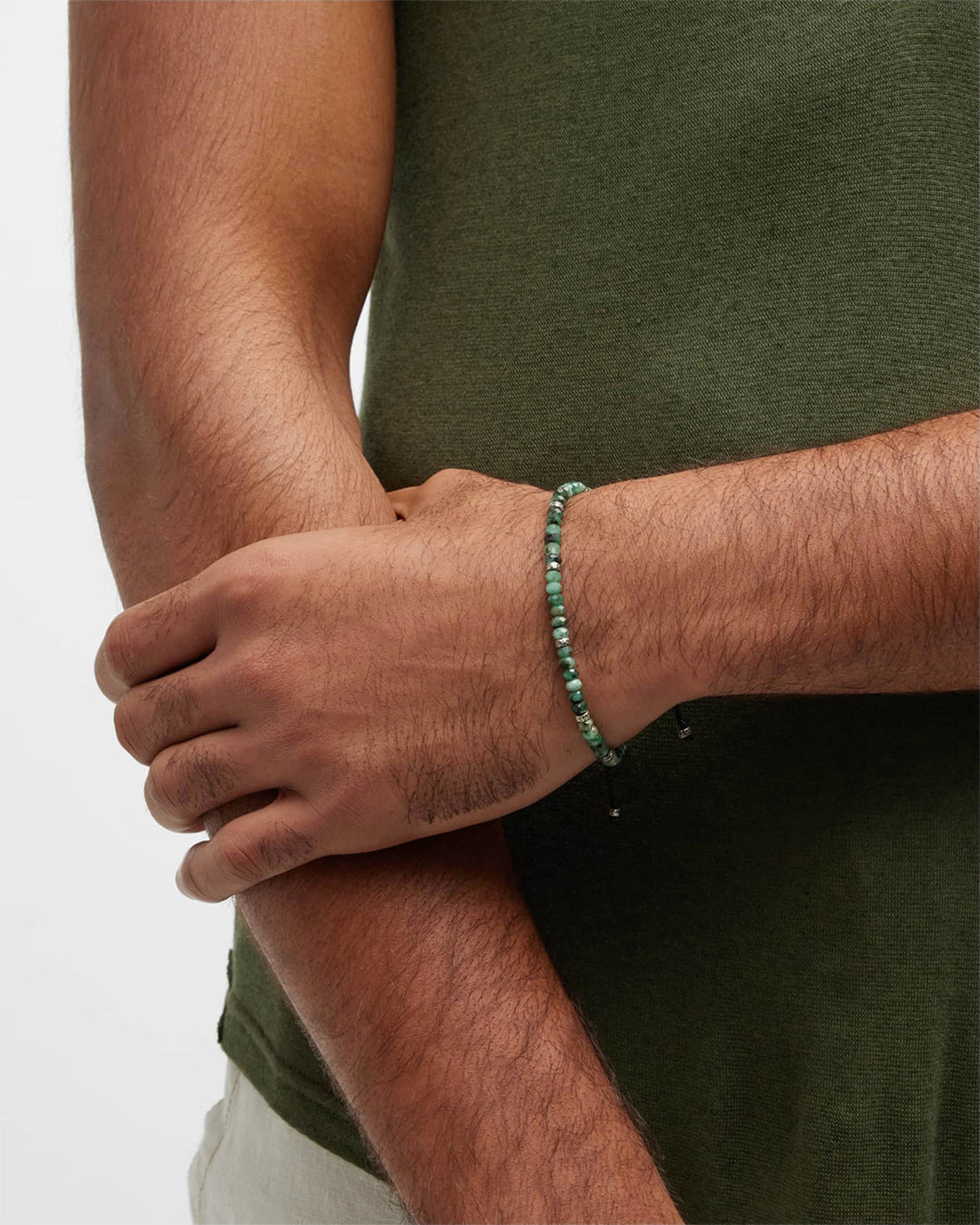 Close up of male models wrist wearing Jan Leslie Faceted Emerald Gemstone Bracelet with Black Pull Cord. 