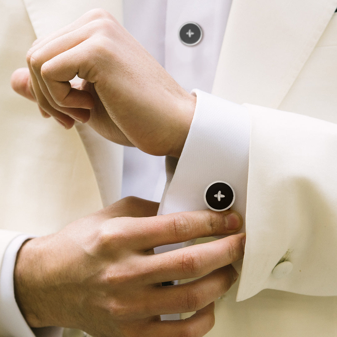 Close up of male models torso showing off the Classic Gemstone Button Sterling Silver Cufflinks and Tuxedo Studs in black onyx on a white cuffed shirt and off white tuxedo jacket. 