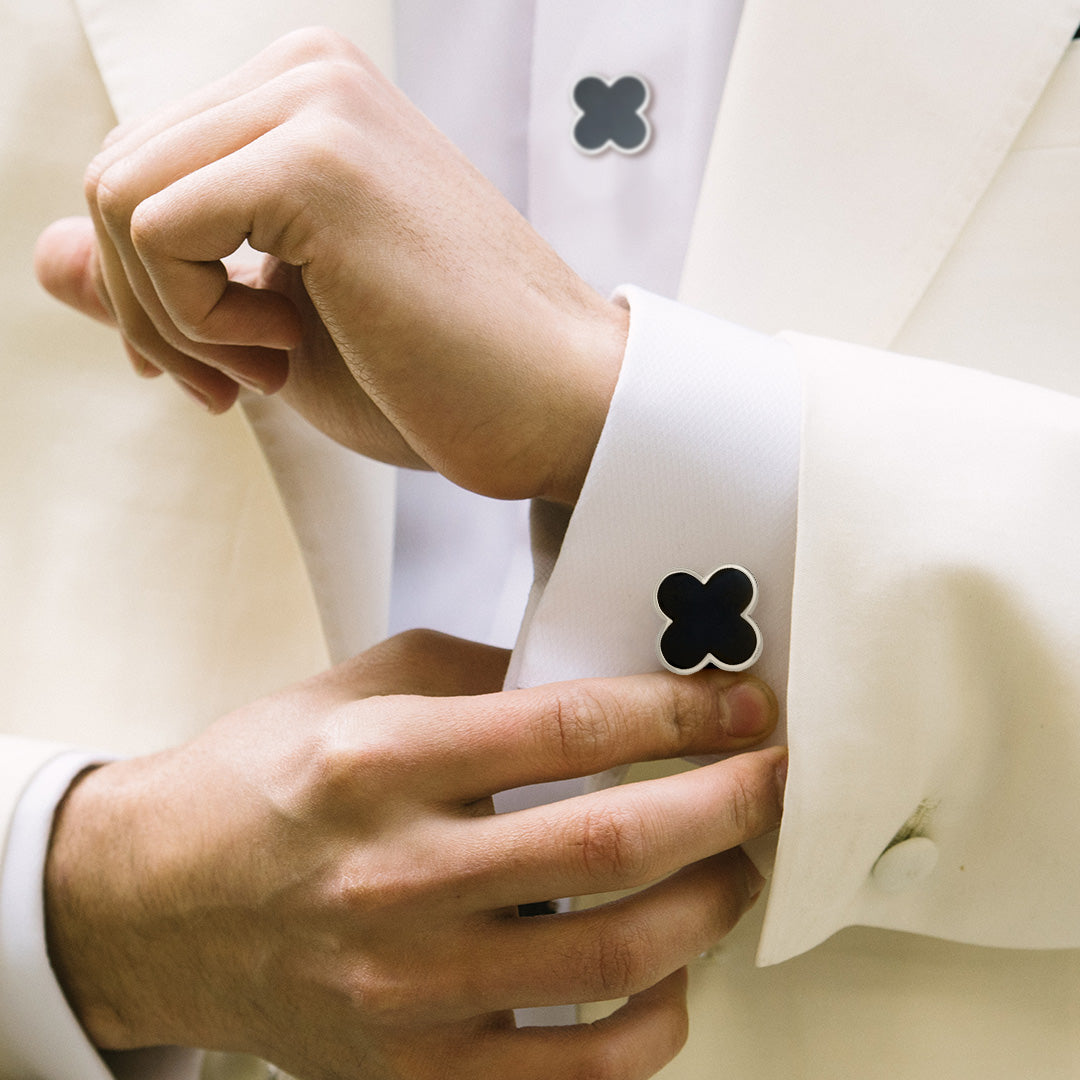 Close up of male models wrist donning Jan Leslie's Onyx Gemstone Four Leaf Clover Sterling Silver Cufflinks and Tuxedo Studs on a white tuxedo shirt with off white tuxedo jacket. 