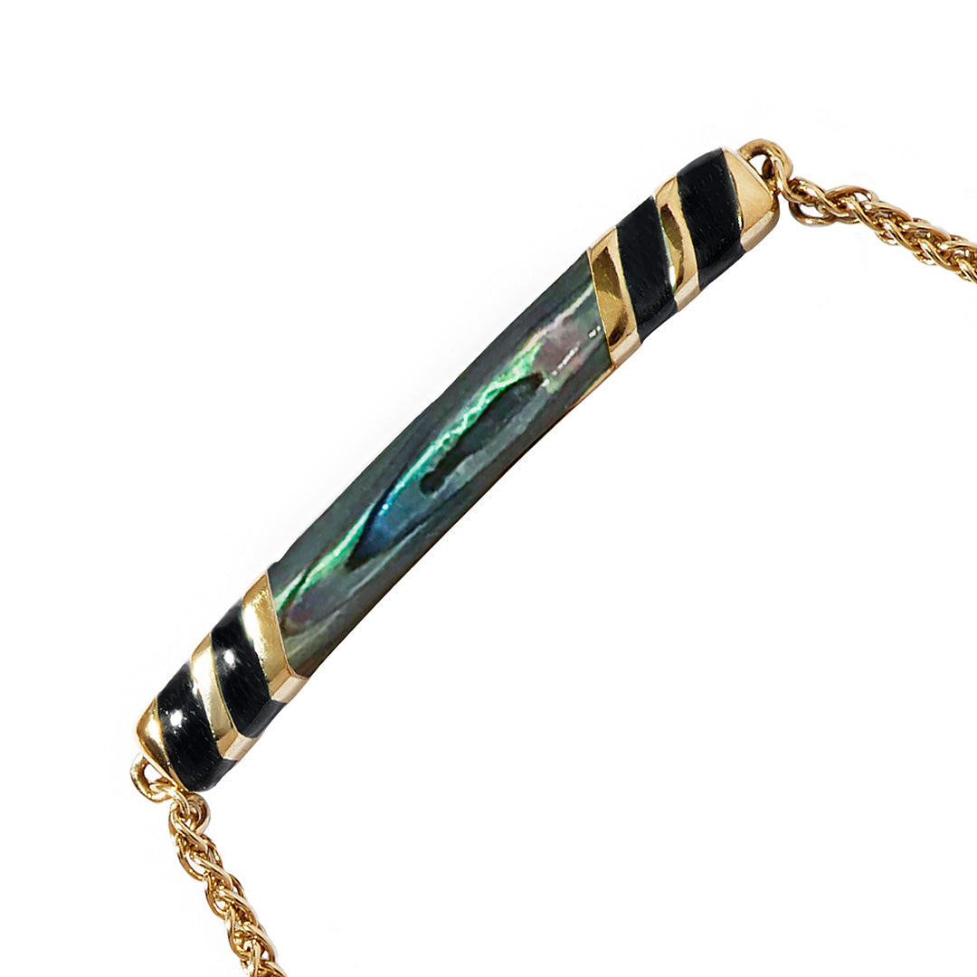 Close up of the Stripe Enamel and Shell Gemstone Adjustable 18K Gold Vermeil Bolo Sterling Silver Bracelet in black on gold. 