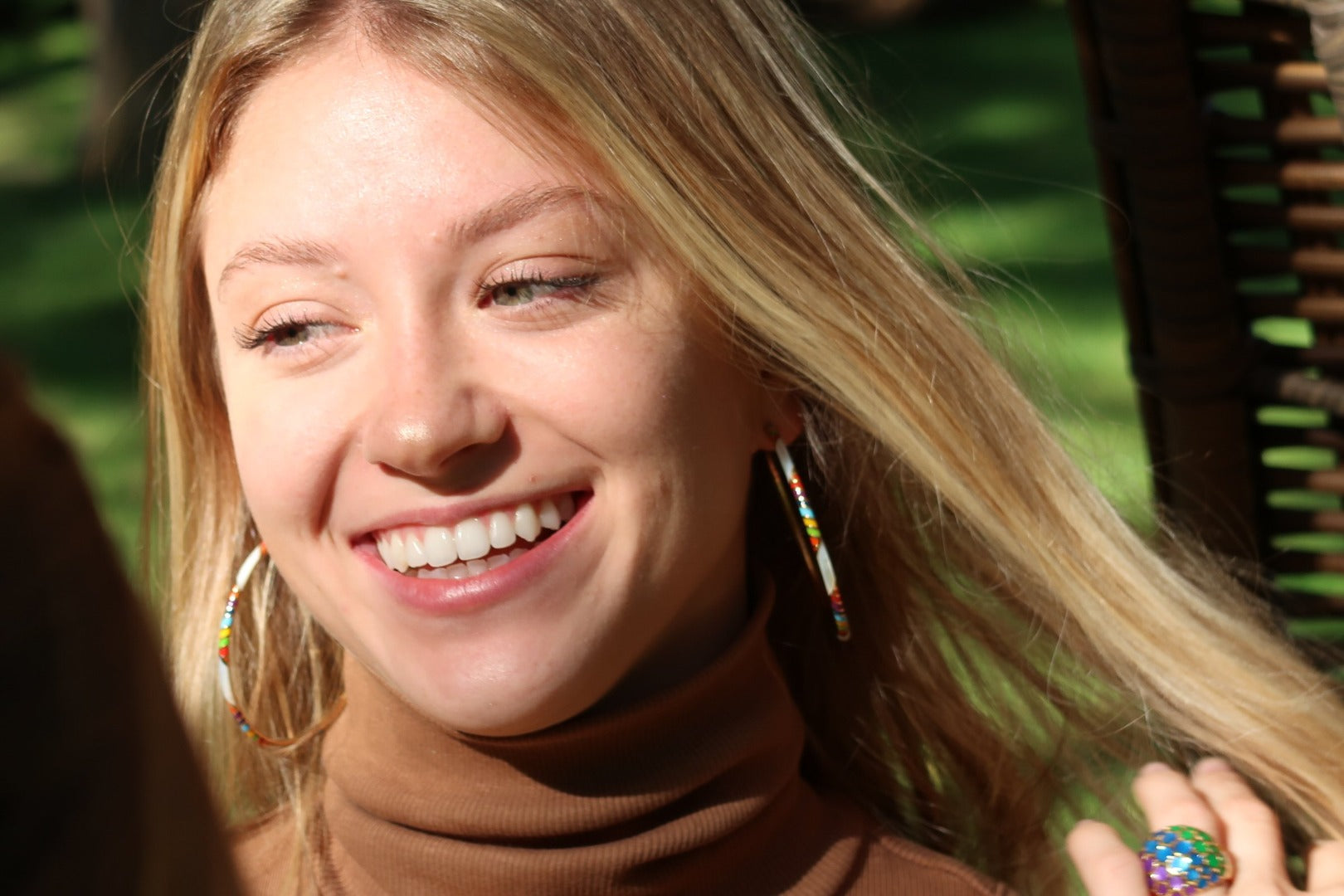 Smiling model wearing Jan Leslie's Orb Mother of Pearl Gemstone and Enamel 18K Gold Vermeil Sterling Silver Ring in rainbow over mother of pearl on gold. 