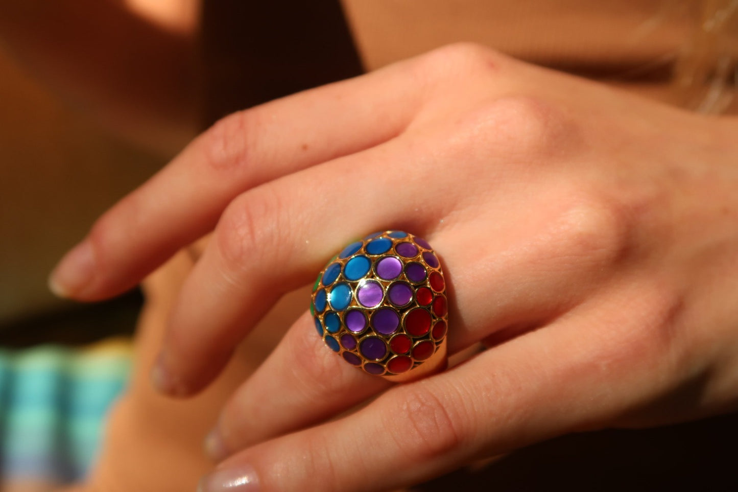 Close up of female models hand donning Jan Leslie's Orb Mother of Pearl Gemstone and Enamel 18K Gold Vermeil Sterling Silver Ring in rainbow over mother of pearl on gold. 