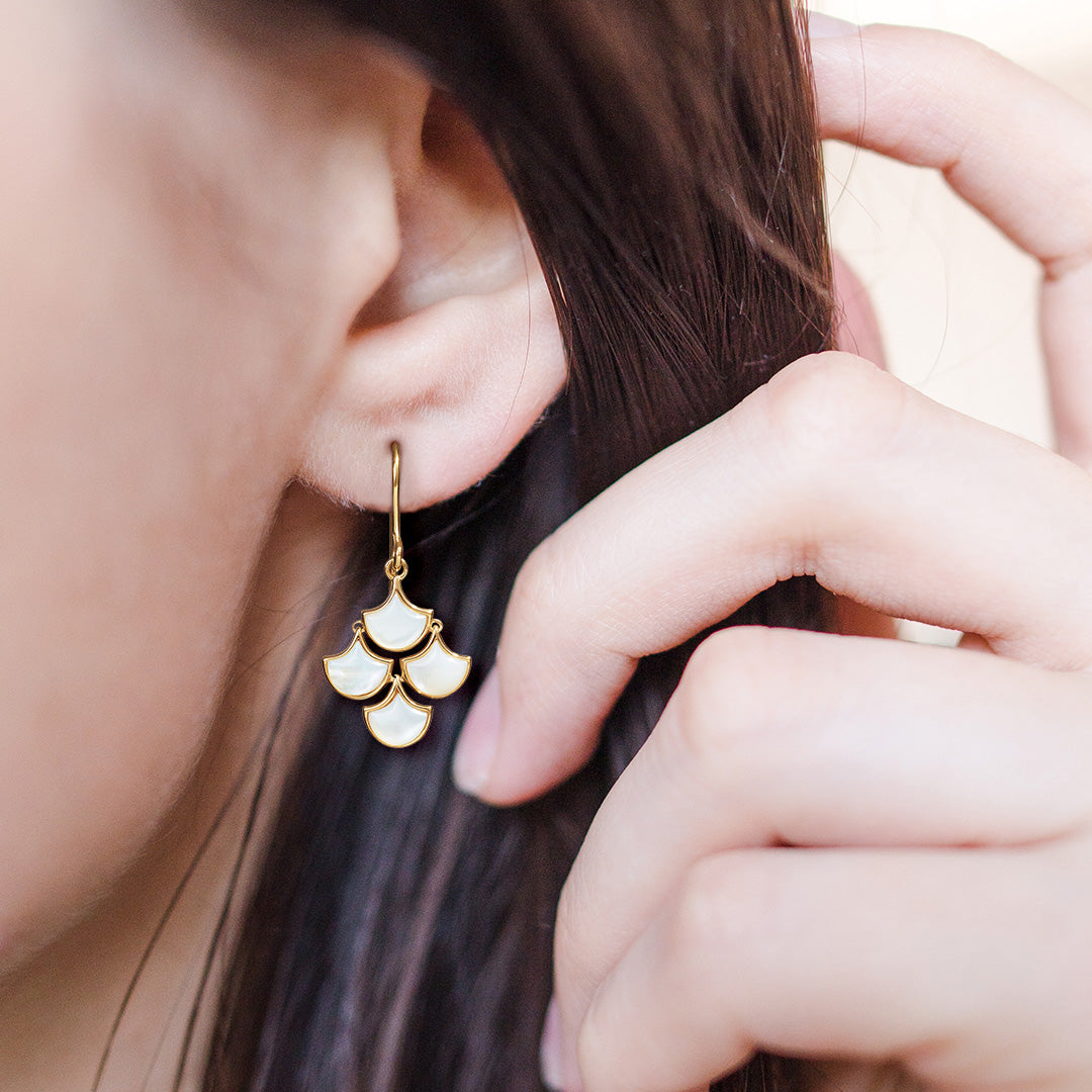 Close up of models ear wearing Koi Cascade Moving Mother of Pearl Earring Petite in white mother of pearl on gold. 