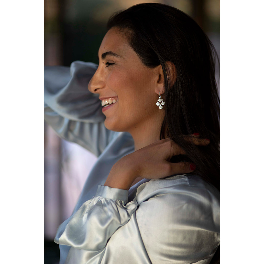 Smiling model wearing Koi Cascade Moving Mother of Pearl Earring Petite in white mother of pearl on silver. 