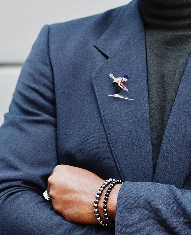 Male model wearing Moving Skier Sterling Silver Lapel Pin on a navy blue suit jacket. 