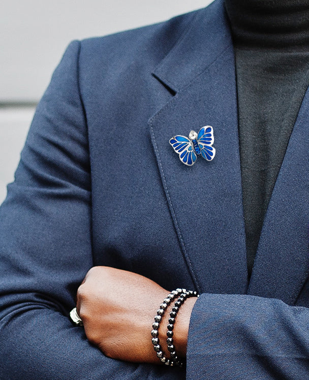 Male model wearing the Hand Painted Enamel Butterfly Sterling Silver Lapel Pin in tonal blue on a navy blue suit jacket. 