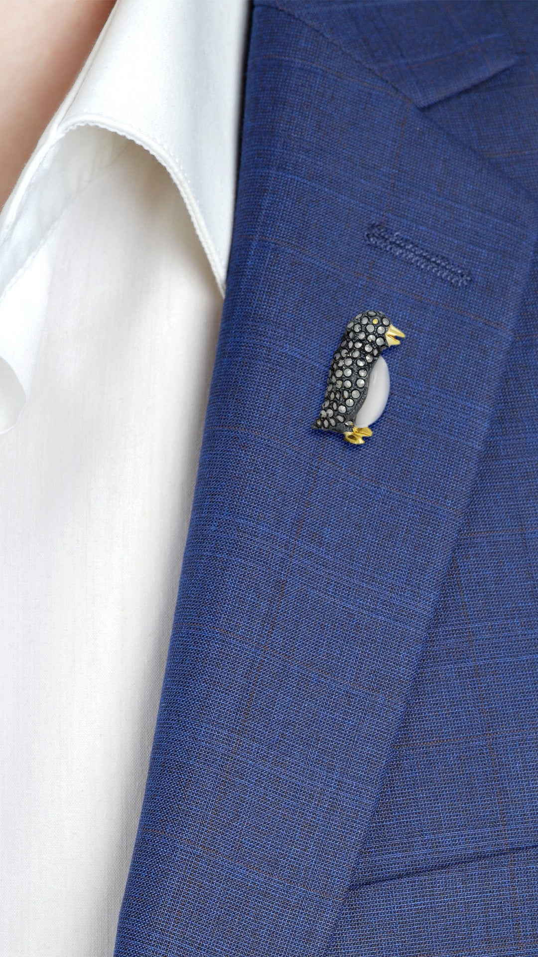 Male model wearing Jan Leslie's Gemstone Penguin Sterling Silver Lapel Pin on a navy blue suit jacket lapel. 