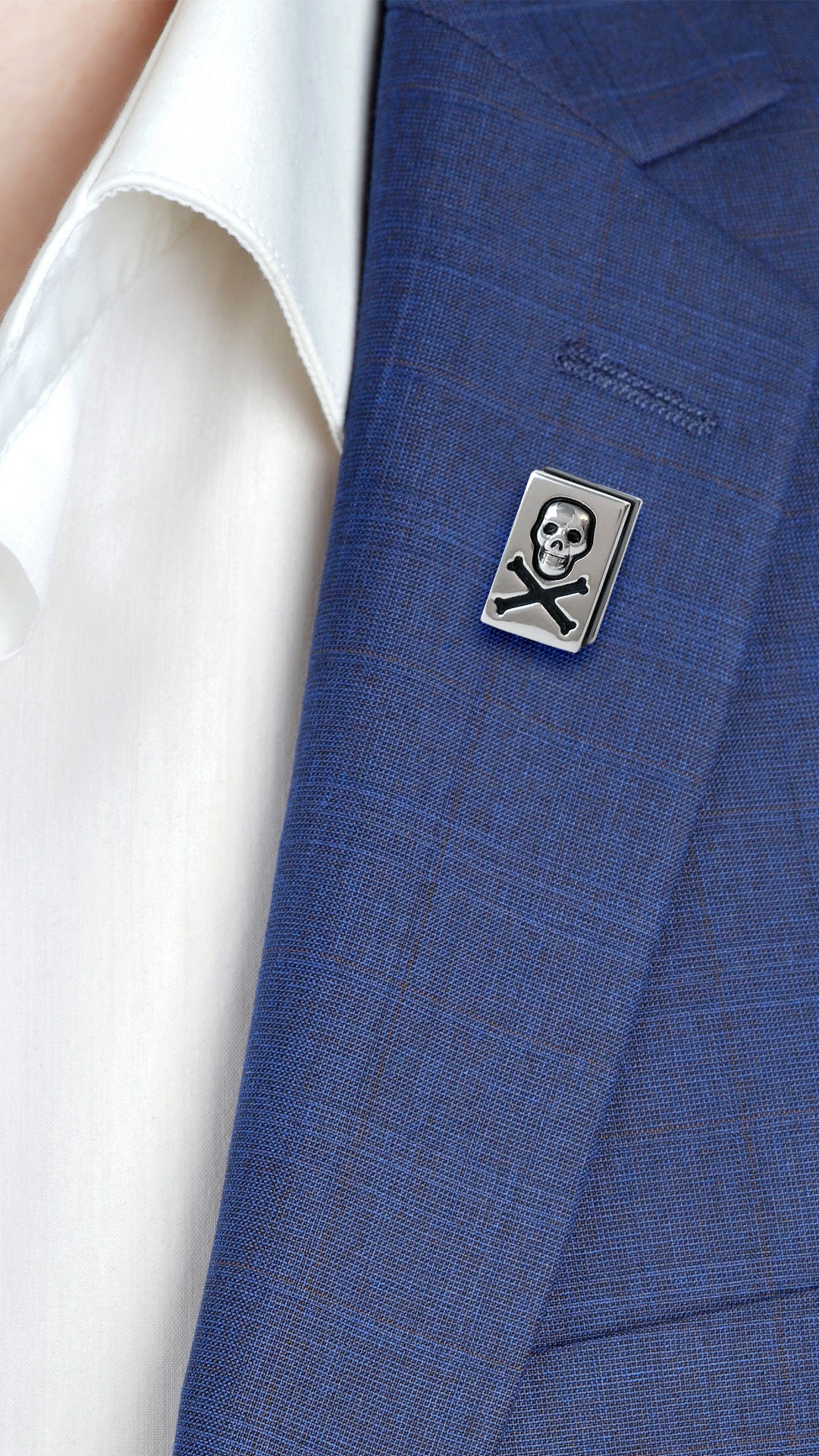 Male model wearing the Skull and Crossbones Sterling Silver Lapel Pin on a blue suit jacket lapel. 