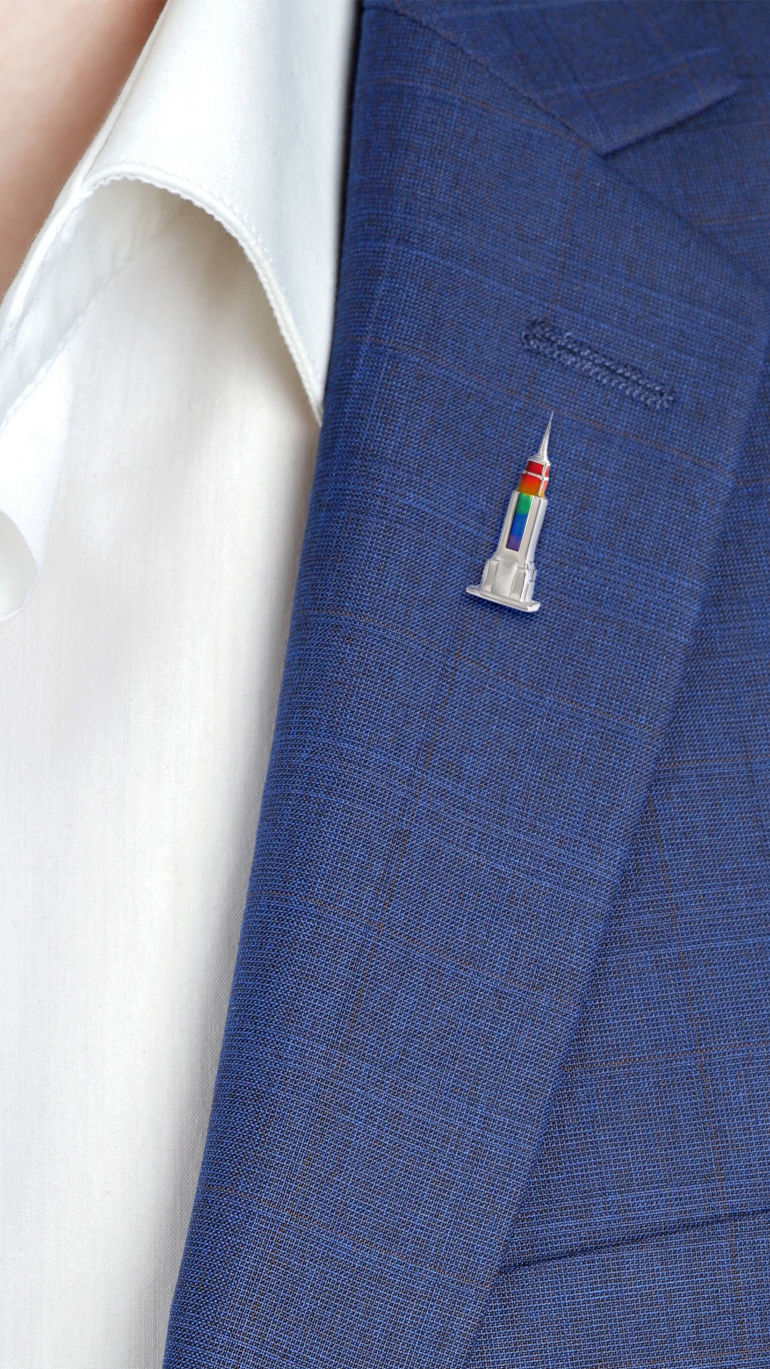 Male model wearing the Rainbow Empire State Building Lapel Pin on a navy blue suit jacket. 