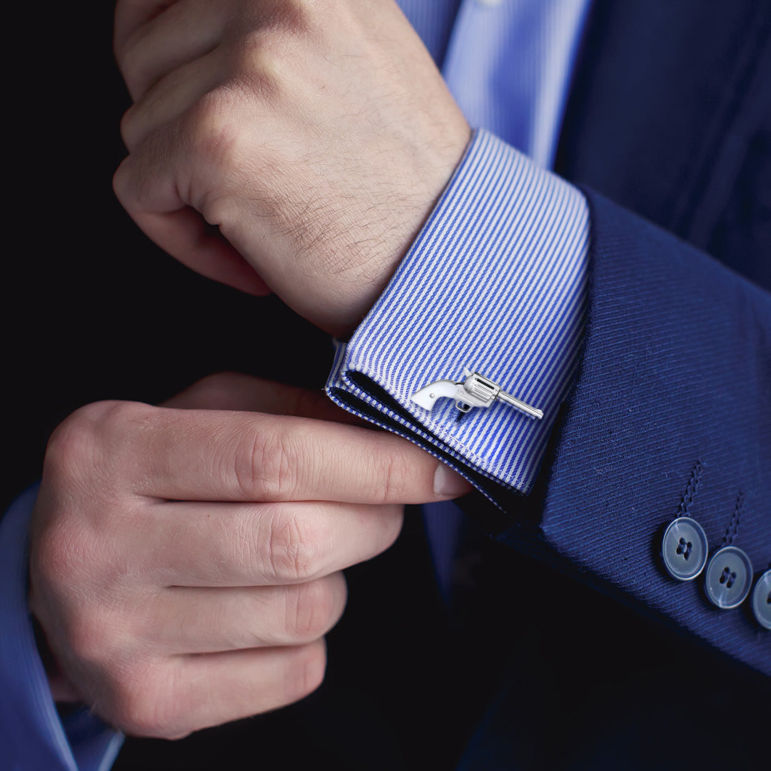 Close up of male models wrist donning the Pistol with Bullet Back Mother of Pearl Sterling Silver Cufflinks on a blue and white striped cuffed shirt with blue sports coat. 