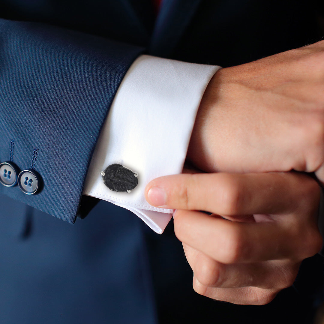 Picture of a male models wrist wearing Delta Trilobite Fossil Sterling Silver Cufflinks on a white cuffed shirt and blue suit jacket. 