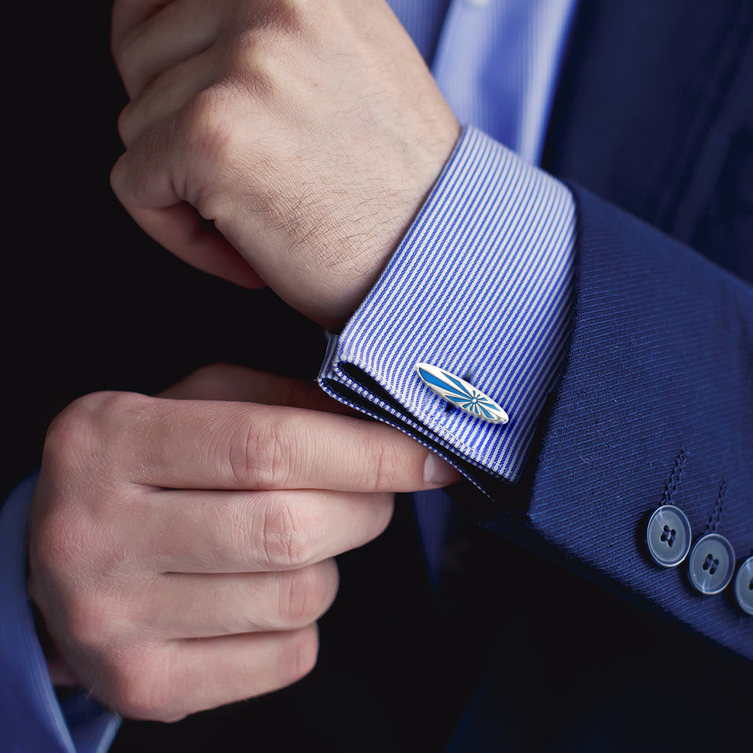 Photo of a man wearing Enamel Retro Surfboard Sterling Silver Cufflinks - Sunburst symbol, with a blue and white striped cuff dress shirt and blue suit jacket.