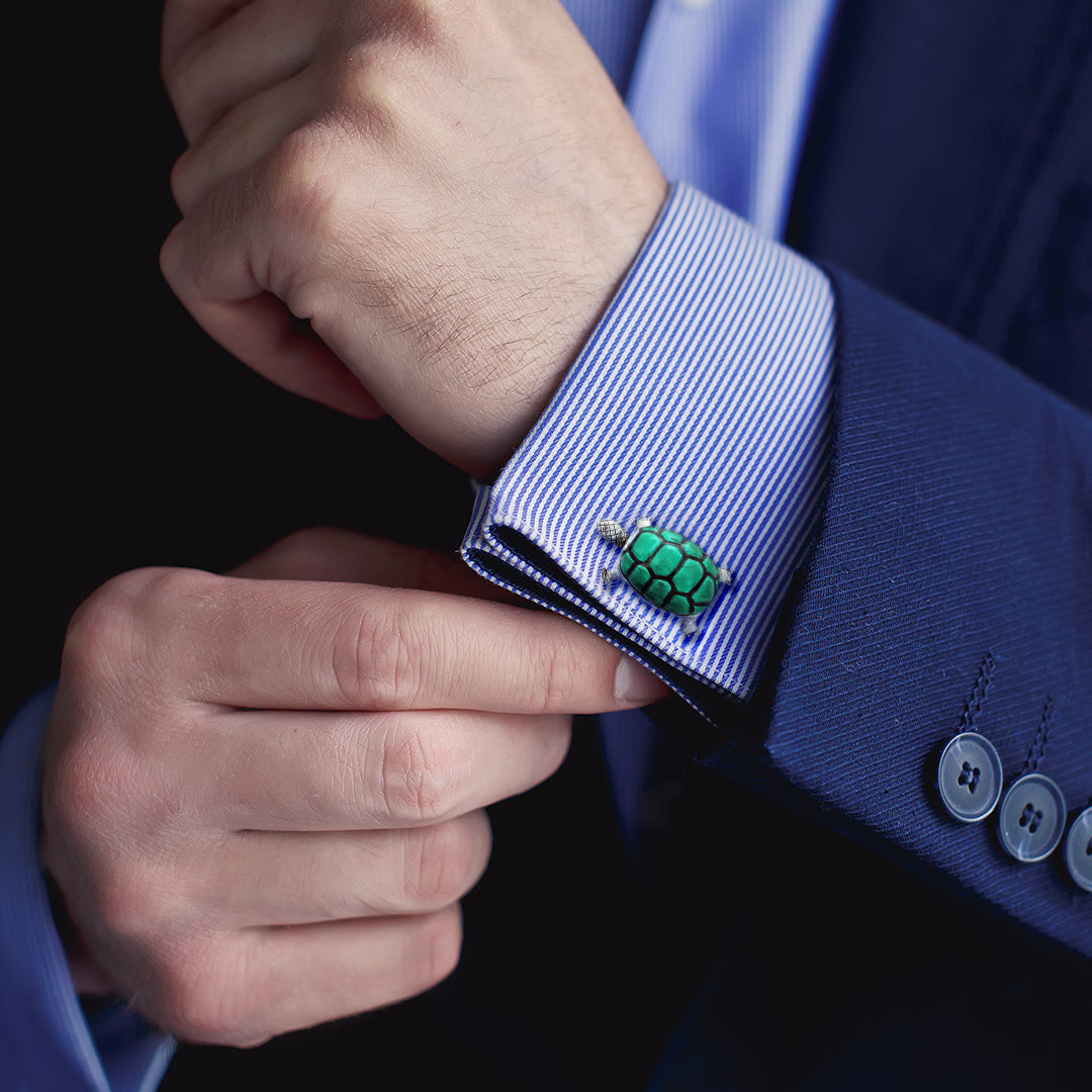  Close up of a male models wrist wearing Jan Leslie Smiling Enamel Shell Turtle Sterling Silver Cufflinks in green on a blue and white striped cuffed shirt with navy blue sports coat. 