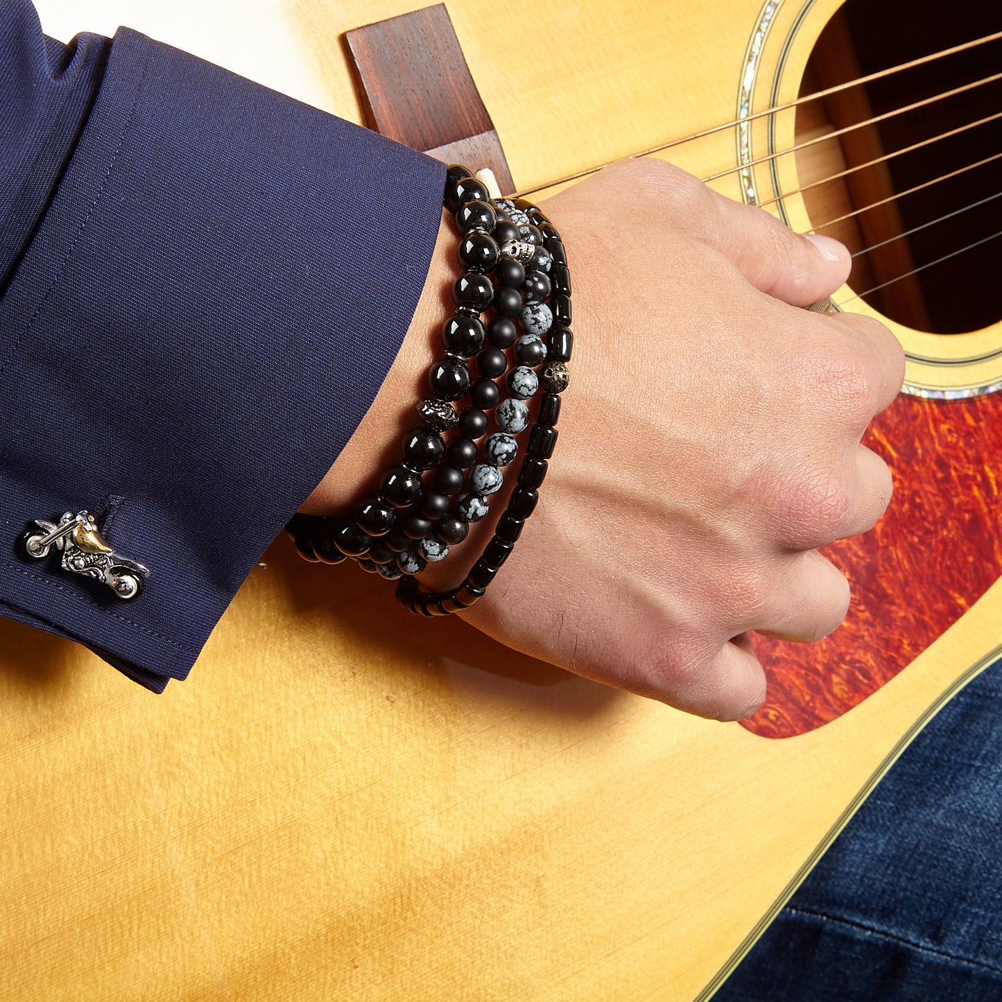 Close-up of models wrist showing off bracelet stack featuring the snowflake obsidian and matte onyx 8mm Gemstone Beaded Elastic Bracelet, and 