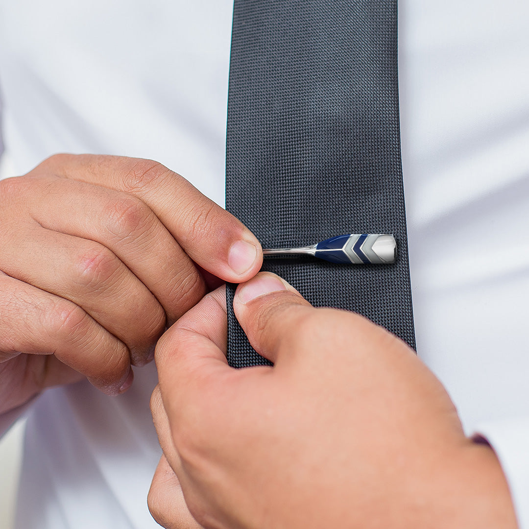 Close up of a male model putting the Chevron Crew Oar Sterling Silver Tie Bar in royal blue and white on a dark gray tie. 